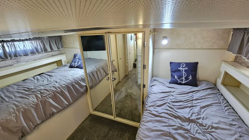 Slide: The Image of The 1971 Chris-Craft 47 Commander cabin features two single beds with gray bedding and an anchor pillow. - 18