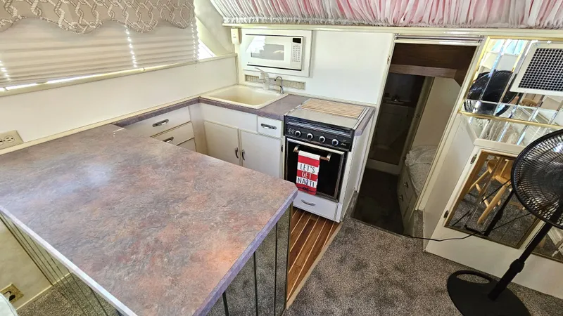 Slide: The Image of The kitchen of a 1971 Chris-Craft 47 Commander with a stove, microwave, and sink. - 36