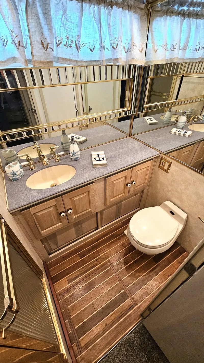 Slide: The Image of An elegant bathroom with wooden flooring, a sink, and a toilet. Mirrors and curtains adorn the space. - 47