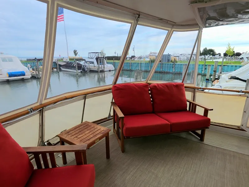 Slide: The Image of The 1971 Chris-Craft 47 Commander features a cozy seating area with red cushions in a marina. - 13