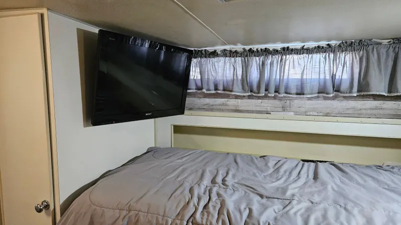 Slide: The Image of A cozy bedroom with a large TV on the wall and a window with curtains. - 38