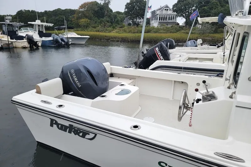 Slide: The Image of 2017 Parker 2120 Sport Cabin boat docked, featuring Yamaha and Suzuki outboard motors. - 6
