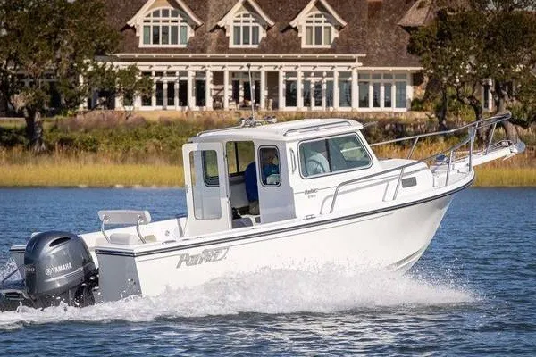 The Image of 2017 Parker 2120 Sport Cabin boat cruising on water near a large house. - 10