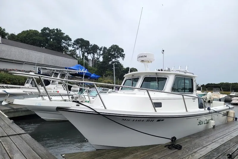 Slide: The Image of 2017 Parker 2120 Sport Cabin boat docked at marina, surrounded by other vessels. - 12