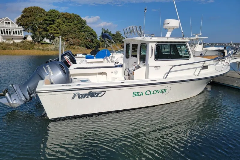 Slide: The Image of 2017 Parker 2120 Sport Cabin boat named "Sea Clover" docked in a serene marina. - 8
