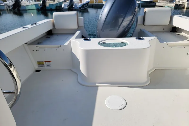 Slide: The Image of 2017 Parker 2120 Sport Cabin boat interior with seating and engine view at marina. - 6