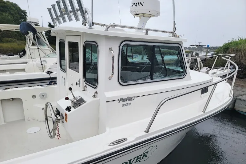 Slide: The Image of 2017 Parker 2120 Sport Cabin boat docked, featuring a sleek white design and spacious cabin. - 1