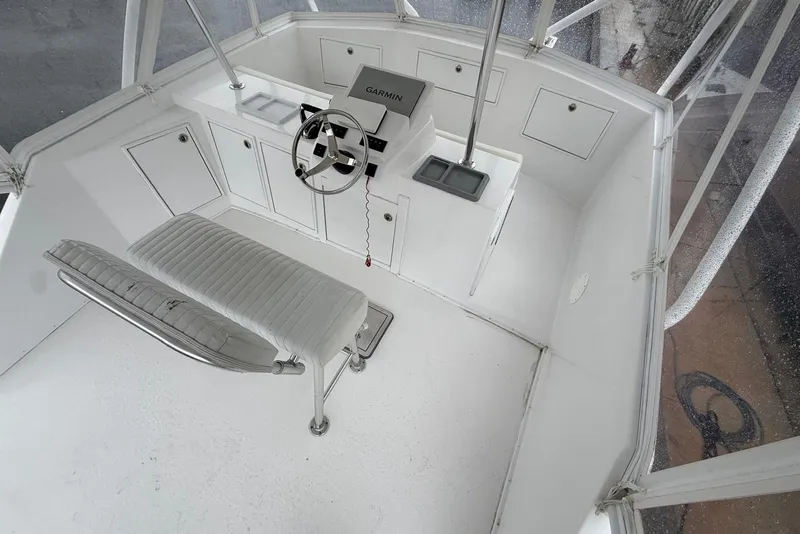Slide: The Image of 1984 Ocean 55 Super Sport helm with Garmin system, white seating, and storage cabinets. - 15