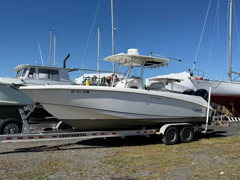 Slide: The Image of A 2006 Boston Whaler 270 Outrage on a trailer, surrounded by other boats in a harbor. - 46