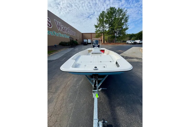 The Image of 2027 Mako Pro Skiff 17 CC boat on trailer, parked outdoors near a warehouse. - 0