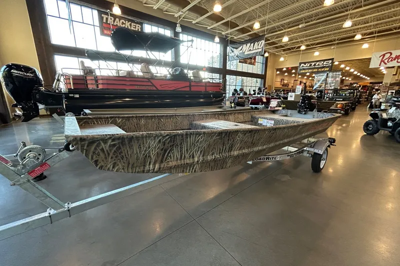 The Image of 2027 Tracker Grizzly 15 Jon boat displayed indoors on a trailer. - 0