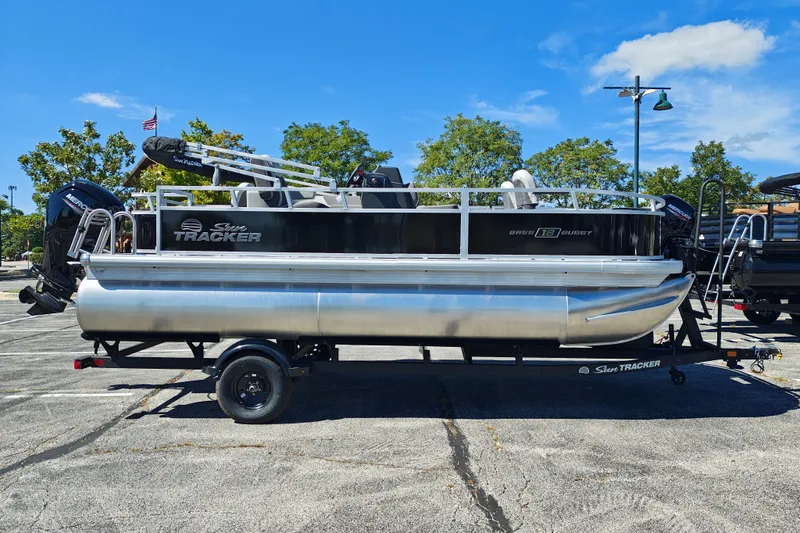 The Image of 2027 Sun Tracker Bass Buggy 18 DLX pontoon boat on trailer, parked outdoors. - 1