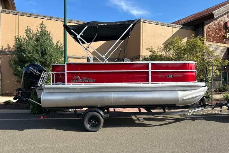 The Image of 2027 Sun Tracker Party Barge 18 DLX pontoon boat on trailer, parked outdoors. - 0