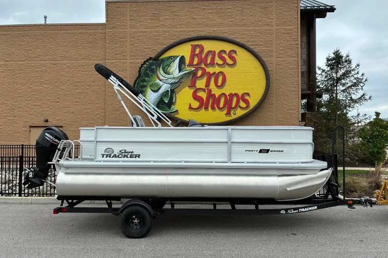 The Image of A 2027 Sun Tracker Party Barge 18 DLX on a trailer in front of a Bass Pro Shops. - 0