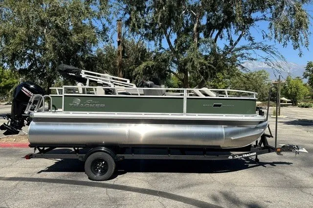 The Image of 2027 Sun Tracker Bass Buggy 18 DLX pontoon boat on trailer, parked outdoors. - 0