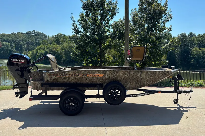 The Image of 2027 Tracker Grizzly 1553 Timber boat on trailer, parked outdoors near trees. - 0