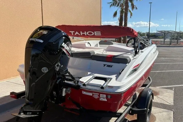 Slide: The Image of 2027 Tahoe T16 boat with Mercury engine, red and white design, parked outdoors. - 3