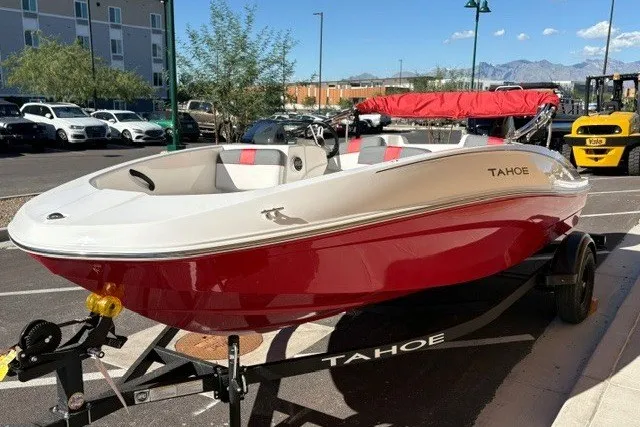Slide: The Image of 2027 Tahoe T16 boat in red and white on a trailer, parked outdoors. - 2