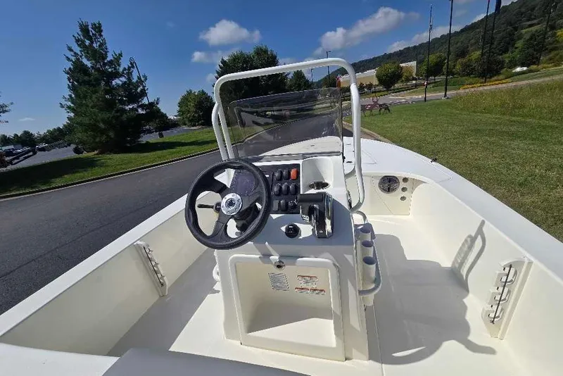 Slide: The Image of 2026 Mako 18 Pro Skiff boat interior with steering wheel and console, parked outdoors. - 5