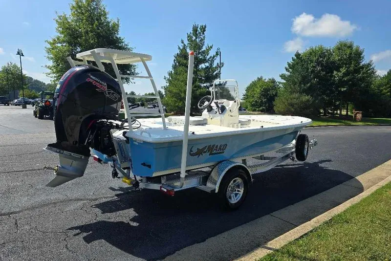 Slide: The Image of 2026 Mako 18 Pro Skiff boat on trailer, parked outdoors under clear sky. - 11