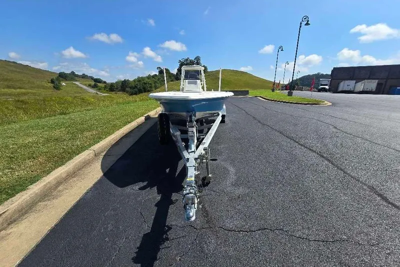 Slide: The Image of 2026 Mako 18 Pro Skiff on trailer, parked on asphalt near grassy hills under blue sky. - 8