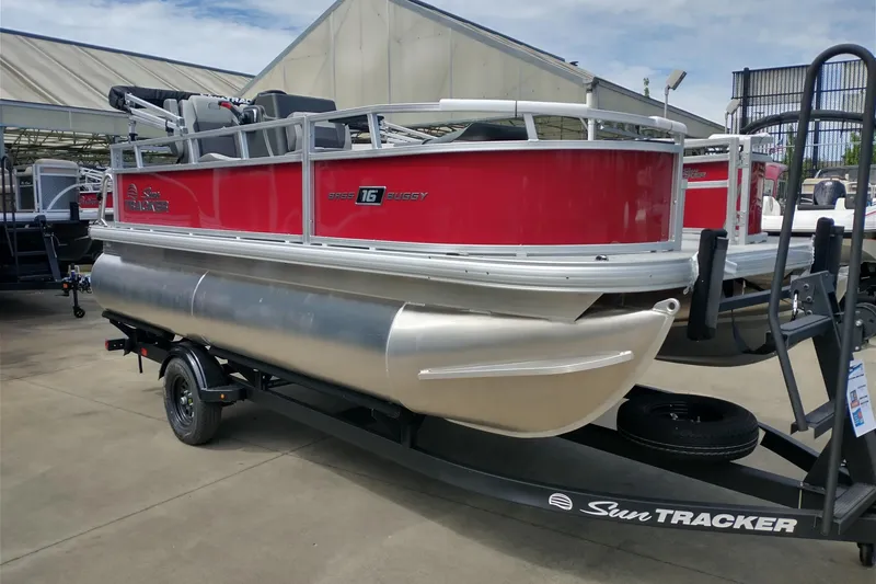 The Image of 2027 Sun Tracker Bass Buggy 16 XL Select pontoon boat on trailer, red and silver design. - 0