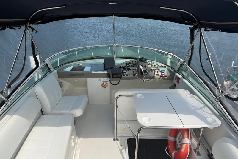 Slide: The Image of 1998 Carver 350 Mariner boat interior with helm, seating, and table on water. - 12