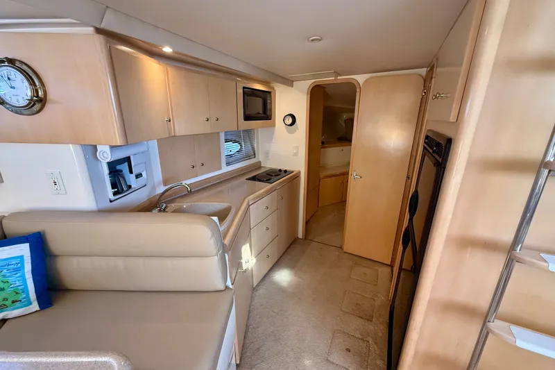 Slide: The Image of Interior of a 1998 Carver 350 Mariner yacht, featuring a compact kitchen and seating area. - 18