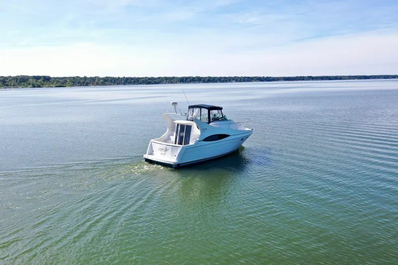 Slide: The Image of 1998 Carver 350 Mariner yacht cruising on a serene lake under a clear blue sky. - 2