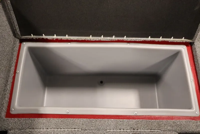 Slide: The Image of 2022 Tracker Targa V-19 WT storage compartment, open lid, gray interior, red trim. - 28