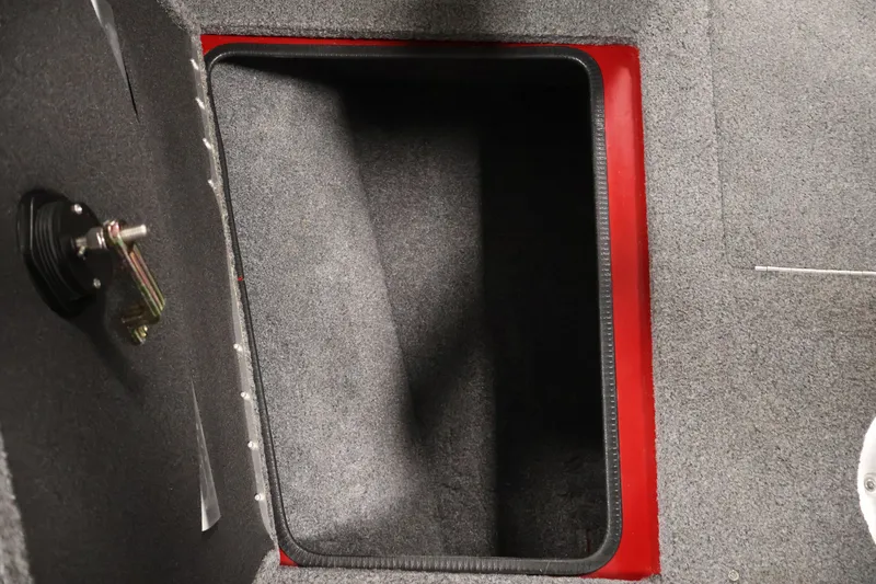 Slide: The Image of Storage compartment in 2022 Tracker Targa V-19 WT boat, featuring gray carpet and red trim. - 21
