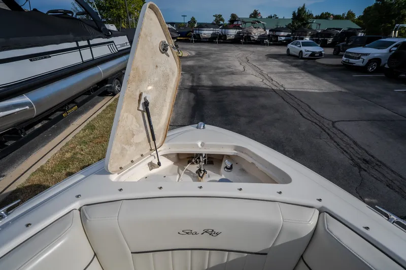 Slide: The Image of 2006 Sea Ray 270 SLX boat with open storage compartment in a marina parking area. - 32