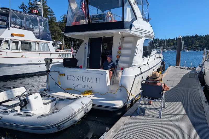 Slide: The Image of 2001 Bayliner 3788 Command Bridge Motoryacht docked with inflatable boat, sunny day. - 2