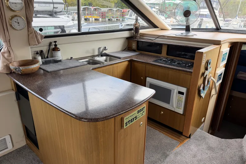 Slide: The Image of 2001 Bayliner 3788 Command Bridge Motoryacht kitchen with sink, stove, and microwave. - 12
