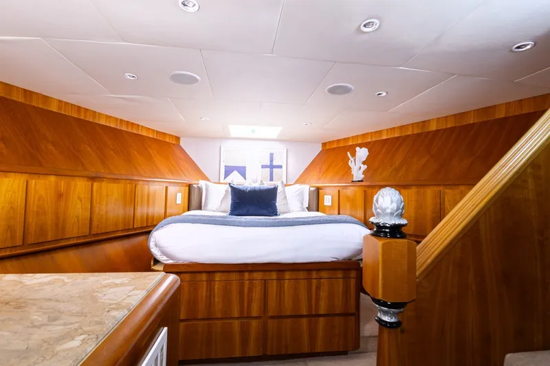 Slide: The Image of Luxurious Broward 110 yacht bedroom with wood paneling and elegant bedding, 2004 model. - 17
