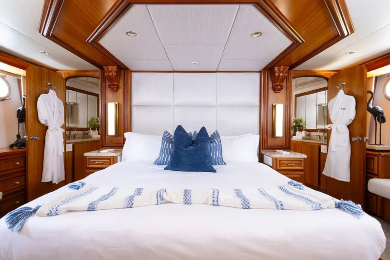 Slide: The Image of Luxurious Broward 110 yacht bedroom, 2004 model, featuring elegant wood finishes and plush bedding. - 18