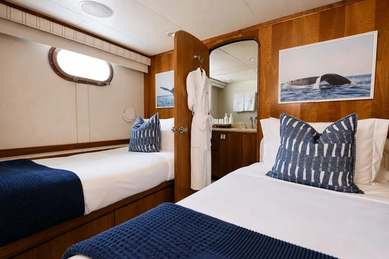 Slide: The Image of Luxurious 2004 Broward 110 yacht cabin with twin beds, nautical decor, and ensuite bathroom. - 15