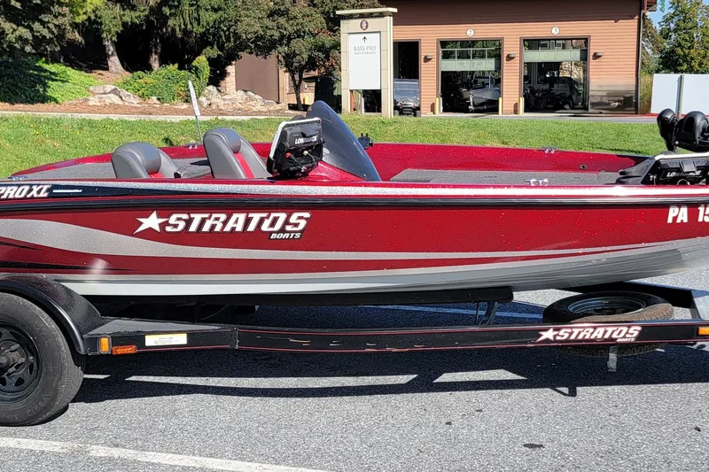 The Image of Red 2004 Stratos 275 Pro XL boat on trailer, parked outdoors near a building. - 0