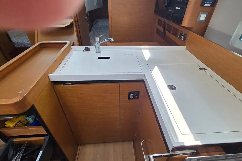 Slide: The Image of Modern kitchen area in a 2020 Jeanneau Sun Odyssey 410 sailboat, featuring sleek cabinetry and sink. - 50