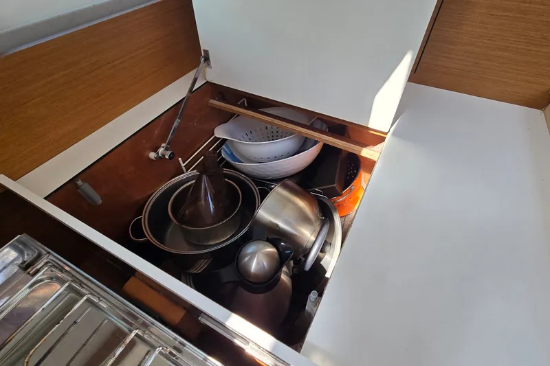 Slide: The Image of Kitchen storage in Jeanneau Sun Odyssey 410 yacht, featuring pots and kitchenware. - 47