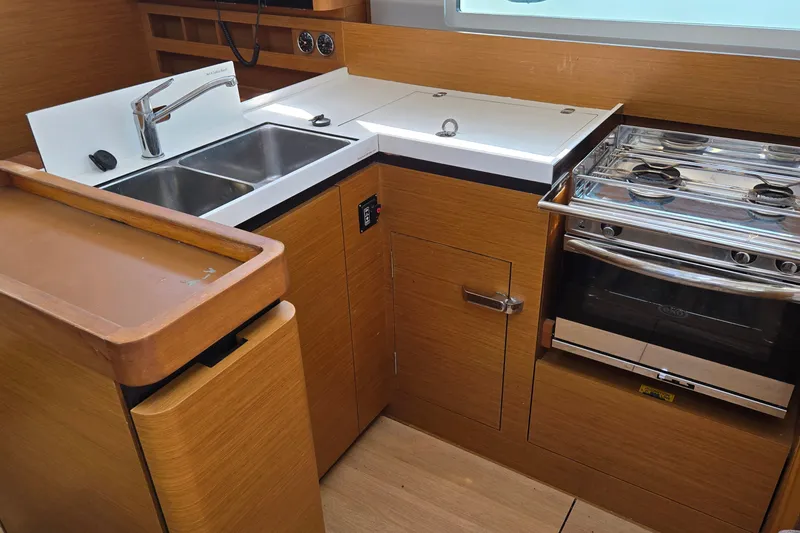 Slide: The Image of Modern kitchen in 2020 Jeanneau Sun Odyssey 410 yacht with stove, sink, and wooden cabinetry. - 33