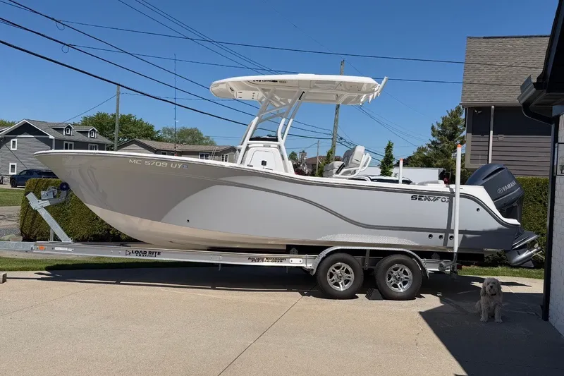 Slide: The Image of 2023 Sea Fox 248 Commander boat on trailer, parked in driveway with a dog nearby. - 2