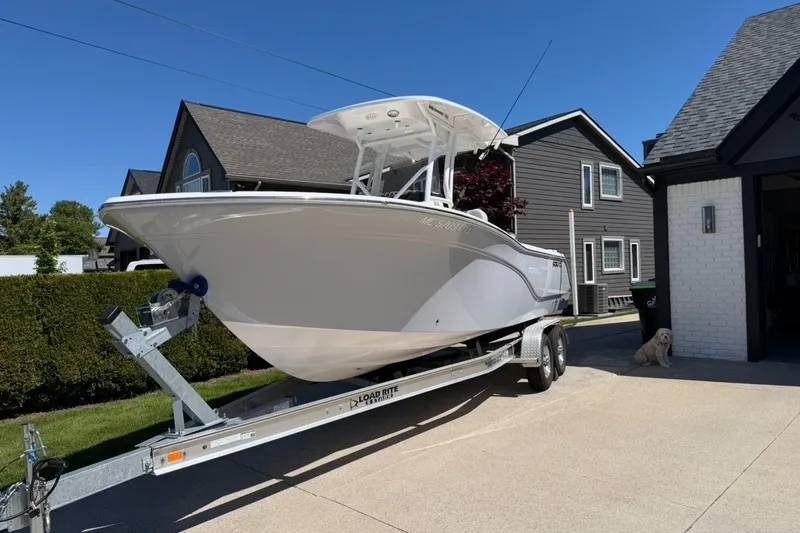 Slide: The Image of 2023 Sea Fox 248 Commander boat on trailer in driveway, with a dog nearby. - 1