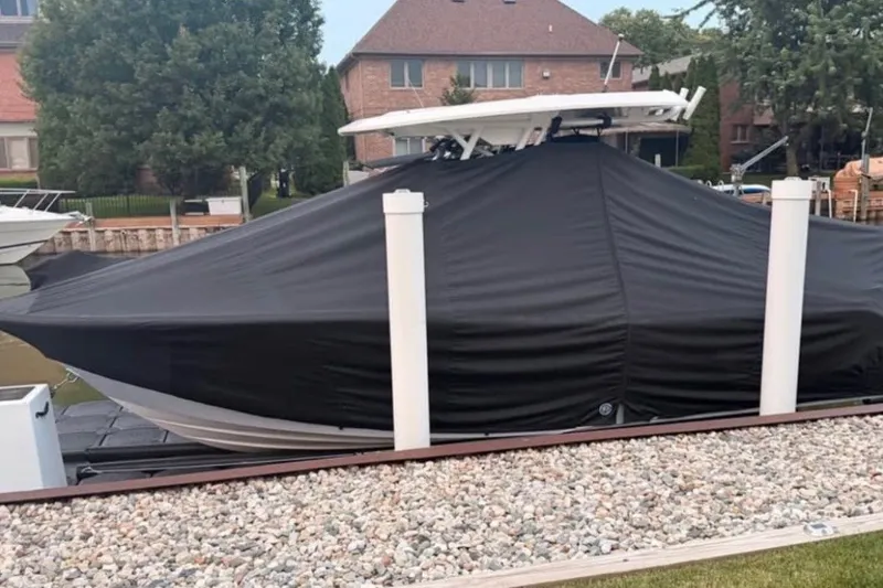 Slide: The Image of 2023 Sea Fox 248 Commander boat covered with a black tarp, docked near waterfront homes. - 7