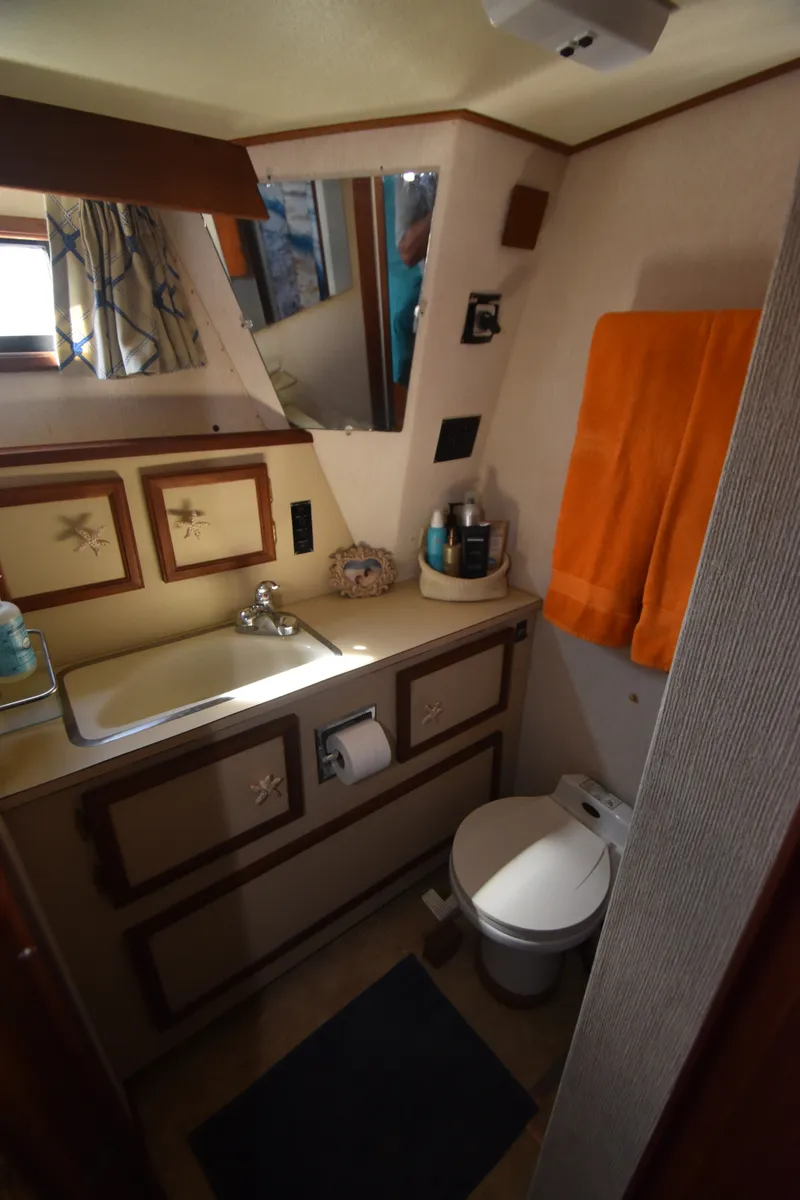 Slide: The Image of Bathroom in a 1981 Viking 43 Aft Cabin with sink, toilet, and orange towel. - 26