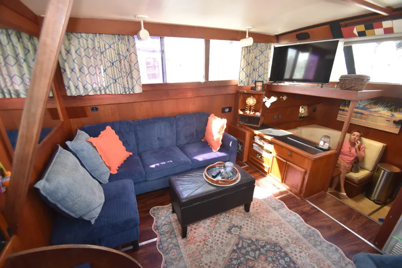 Slide: The Image of The image shows the cozy salon of a 1981 Viking 43 Aft Cabin with blue sofas and wood furnishings. - 18