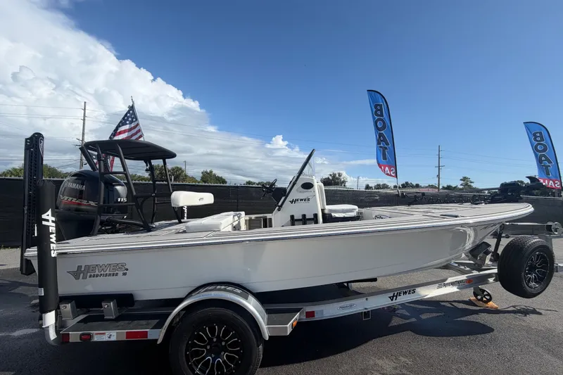 The Image of 2022 Hewes Redfisher 16 boat on trailer, displayed outdoors with flags and clear sky. - 0
