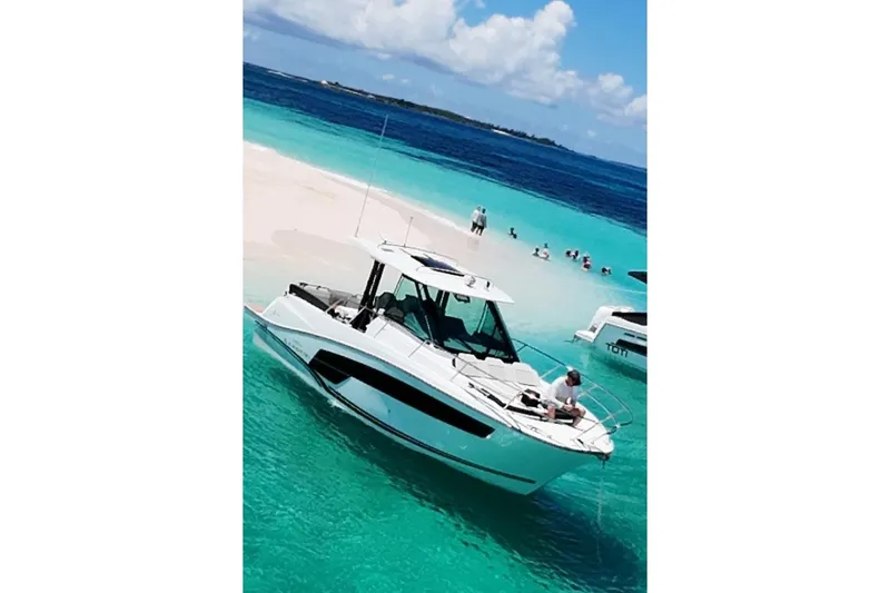 Slide: The Image of 2025 Jeanneau Leader 10.5 WA Series 2 boat anchored on turquoise water near sandy beach. - 22