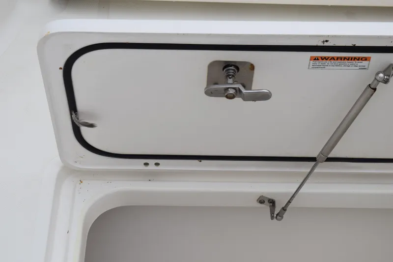 Slide: The Image of 2022 Pursuit OS 355 Offshore boat compartment with latch and warning label. - 140