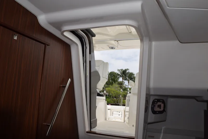 Slide: The Image of Interior view of 2022 Pursuit OS 355 Offshore boat, featuring sleek wooden door and cockpit access. - 358